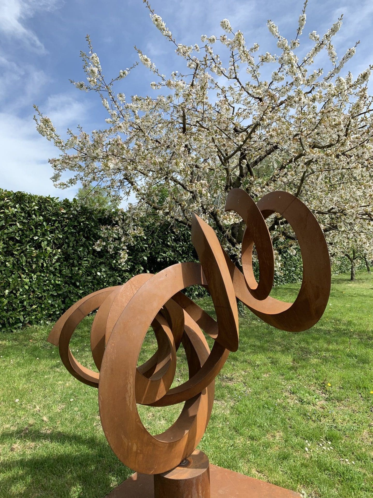 Sculpture de Pieter Obels entouré d'arbres en fleurs.